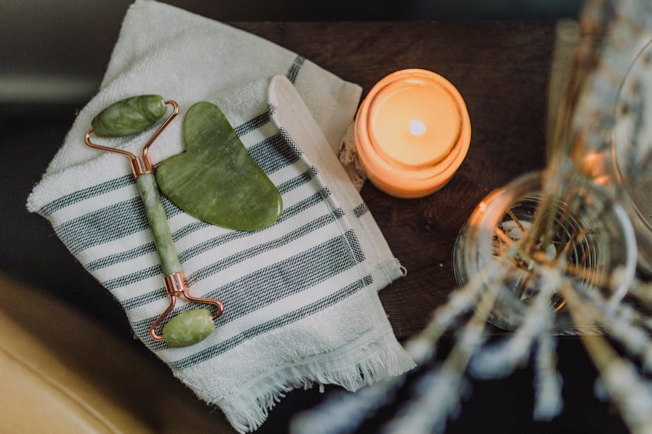 A serene spa setup featuring a jade roller, gua sha, towel, and candle for ultimate relaxation